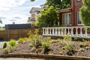 einen Garten vor einem Haus mit weißem Geländer in der Unterkunft Graham Apartments in Hobart