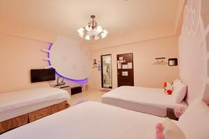 a room with two beds and a tv at Love and Peace B&B in Taitung City