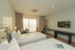 a hotel room with two beds and a flat screen tv at Dana Pearl Bay in Danang