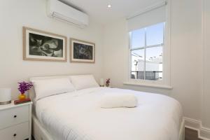 Un dormitorio blanco con una cama blanca y una ventana en Renovated Terrace-Style Apartment in Woollahra, en Sídney