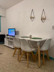 mesa de comedor con sillas blancas y ordenador portátil en Depto Zona Guemes en Mar del Plata