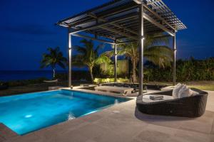 a swimming pool with a pergola next to the ocean at Ananda House estate in Governorʼs Harbour