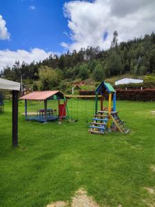 a playground with play equipment in a grass field at Villa Libertad in Paipa