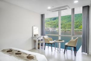 a bedroom with a bed and chairs and a large window at YJ Hotel in Gapyeong