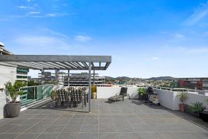 a patio with tables and chairs on a roof at Stadium Vue, 3Bd,Riverview Pool, 300m to S/Stadium in Brisbane