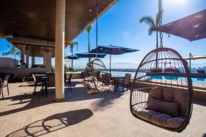 une terrasse avec des balançoires et des chaises ainsi qu'une piscine dans l'établissement Beautiful 3BR Condo with amazing rooftop terrace, à Nuevo Vallarta