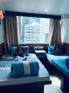 two beds in a room with a large window at United Co-Operate Guest House (7/F) in Hong Kong
