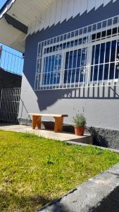 un banco de madera sentado frente a un edificio en Recanto Benedetti, casa para temporada, en Campos do Jordão