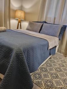 a blue bed with a blue blanket and a lamp at Apartamento inteiro 30 metros do mar in Balneário Camboriú