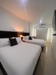 duas camas grandes num quarto de hotel com televisão em Hotel Zuriel Boutique em Cartagena das Índias