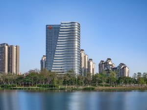 un edificio alto junto a un gran cuerpo de agua en Sheraton Guangzhou Nansha Hotel, en Guangzhou