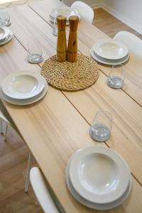 a wooden table with white plates and wine glasses at Beltana - Aldinga Beach - C21 SouthCoast Holidays in Aldinga Beach