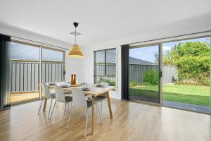 - une salle à manger avec une table, des chaises et de grandes fenêtres dans l'établissement Beltana - Aldinga Beach - C21 SouthCoast Holidays, à Aldinga Beach