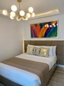 a bedroom with a large bed with a painting on the wall at MAKATI Isabela Luxury in Manila