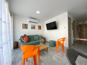 a living room with a blue couch and orange chairs at Apartamento en condominio con vista al mar in San Bernardo del Viento