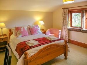 - une chambre avec un grand lit et des oreillers roses dans l'établissement Cairngarth Cottage, à How