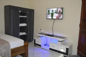 a bedroom with a bed and a tv on a wall at Deluxe Studio Apartment - Royal Palms - Mtwapa in Shimo la Tewa