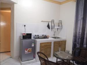 a kitchen with a stove and a sink and a table at Deluxe Studio Apartment - Royal Palms - Mtwapa in Shimo la Tewa
