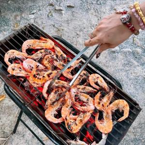 a person is cooking shrimp on a grill at Ingtarn Ressort At thasala in Ban Nai Thung