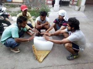 um grupo de homens sentados em torno de um recipiente branco em Saspolo chain of G house em Skardu