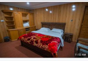 um quarto com uma cama grande com um cobertor vermelho em Saspolo chain of G house em Skardu