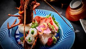 a blue plate of food with a sandwich and vegetables at Tamaya Ryokan in Ueda