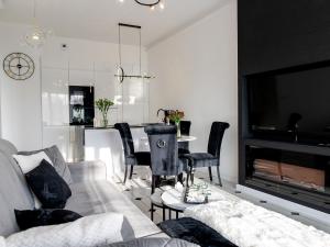 a living room with a couch and a tv and a table at Apartment by Dziwna River with Pool Access in Dziwnów