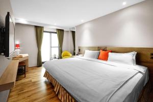 a bedroom with a large white bed with orange pillows at Lan Kwai Fong Garden Hotel in Chiayi City