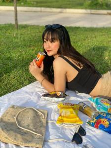 una mujer sentada en una manta de picnic sosteniendo una bebida en L'ama Villa Đại Lải - Venuestay en Phúc Yên