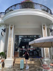 Phúc YênにあるL'ama Villa Đại Lải - Venuestayのスーツケースを持つ建物前に立つ女性