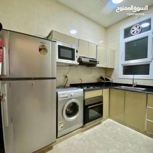 a kitchen with a refrigerator and a washing machine at مجمع الحديقة in Salalah