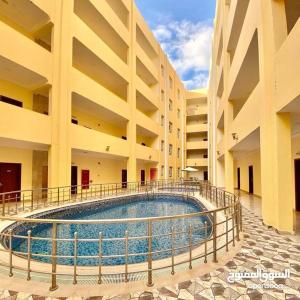 a large building with a swimming pool in the middle at مجمع الحديقة in Salalah