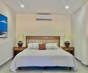 a bedroom with a white bed with two nightstands and two lamps at 5th Av Studio Close to the Beach ADO Ferry & Mall in Playa del Carmen