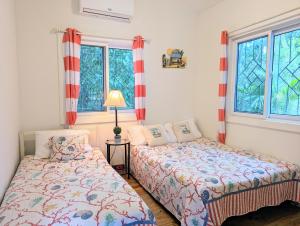 a bedroom with two beds and two windows at West Bay Roatan - Sunny & Modern Oasis- 2 Bedrooms - 3 min walk to beach in Roatán