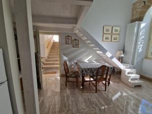 comedor con mesa, sillas y escaleras en La casa di Carmen, en Melfi