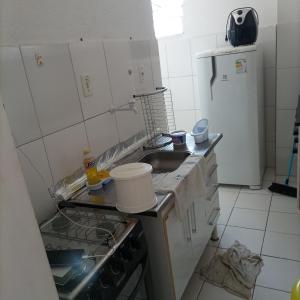 La cuisine est équipée d'un évier, d'une cuisinière et d'un réfrigérateur. dans l'établissement Apartamento no vila Olímpia mobiliado, à Feira de Santana