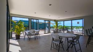 a dining room with tables and chairs and windows at Riviera Home - New 2BR Condo w. big Pool & Jacuzzi in Playa del Carmen