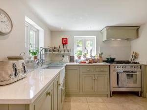 a kitchen with white appliances and a clock on the wall at Hope Cottage in Ilketshall Saint Andrew