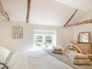 a white bedroom with a bed and a window at Hope Cottage in Ilketshall Saint Andrew