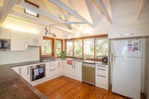 a kitchen with white cabinets and a ceiling fan at 20 Yarrong Road Close to Cylinder Beach in Point Lookout