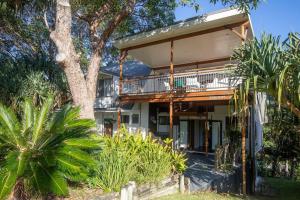 a house with a balcony and a tree at 20 Yarrong Road Close to Cylinder Beach in Point Lookout