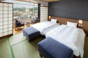 a hotel room with two beds and a balcony at Hotel Sakura Ureshino in Ureshino