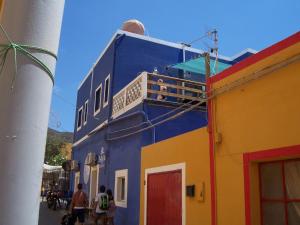 a blue and yellow building with people on the balcony at Casa Blu in Linosa
