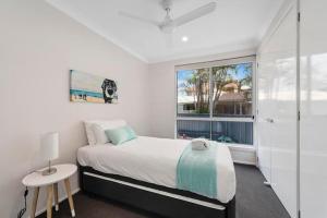 a white bedroom with a bed and a window at Del Boca Vista in Emerald Beach