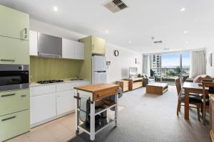 a kitchen with green and white cabinets and a table at Belle Escapes - Getaway on Colley in Glenelg