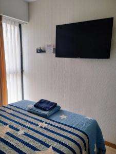 a bedroom with a bed with a flat screen tv on the wall at Habitación con baño privado desayuno incluído en casa de familia in Lima