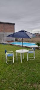einen Tisch mit einem Regenschirm neben zwei Stühlen in der Unterkunft ANELEY Casa De Vacaciones in La Merced