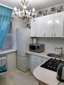 eine Küche mit weißen Schränken und einem Kronleuchter in der Unterkunft Sunny Home Apartment in Dnipro