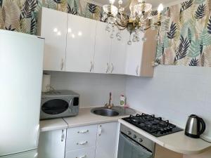 a kitchen with white cabinets and a sink and a microwave at Sunny Home Apartment світло є завжди in Dnipro