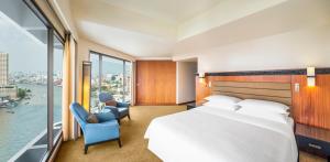 um quarto de hotel com uma cama grande e uma janela grande em Royal Orchid Sheraton Hotel and Towers em Banguecoque